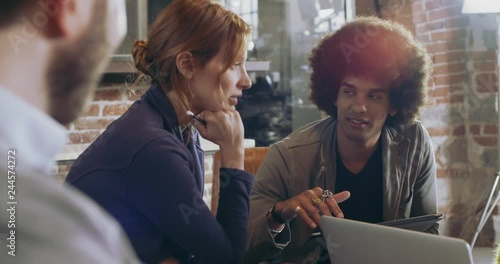 Colleagues and clients talking strategy with laptop and tablet.Group of multiethnic people having informal business team meeting in restaurant lounge.Teamwork,corporate,diversity and social concepts