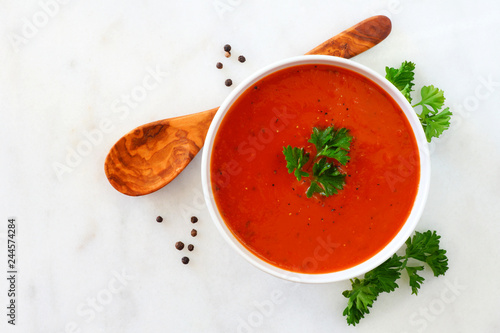 Homemade tomato soup. Top view, simple table scene on a bright granite background.