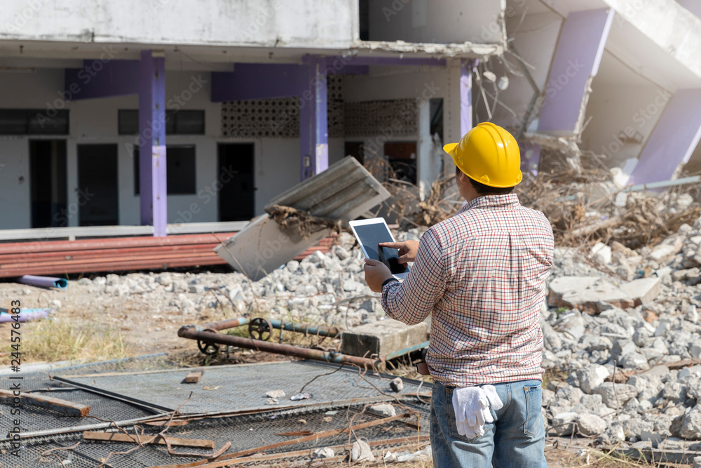 Engineer holding tablet is checking for destruction, demolishing building. Engineer holding tablet is checking for destruction, demolishing building.
