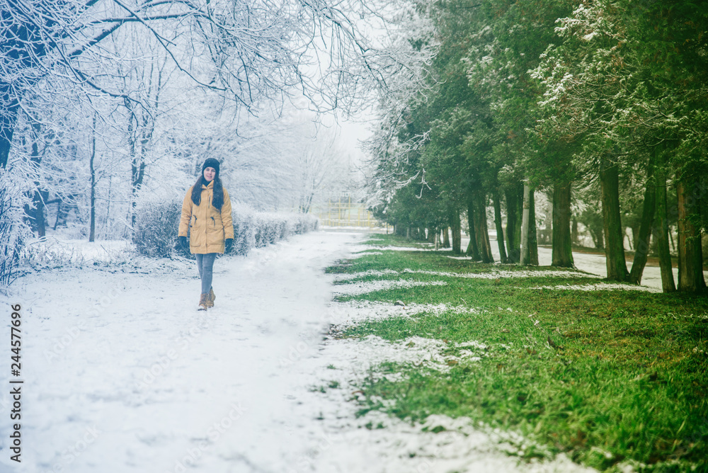 woman walk by park where winter meet spring woman walk by park where winter meet spring