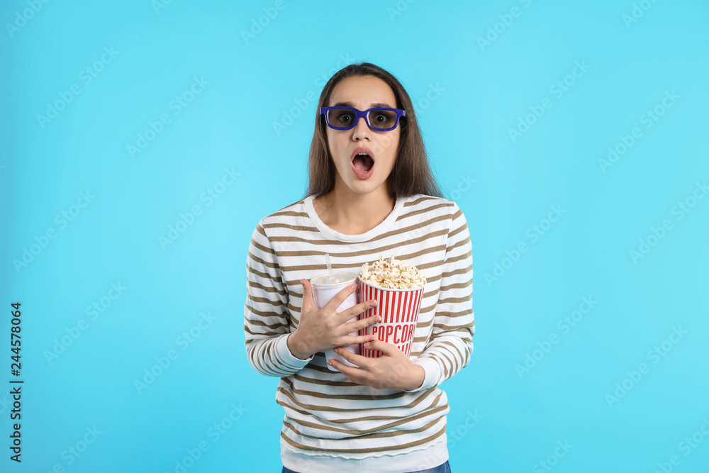 Fototapeta premium Emotional woman with 3D glasses, popcorn and beverage during cinema show on color background