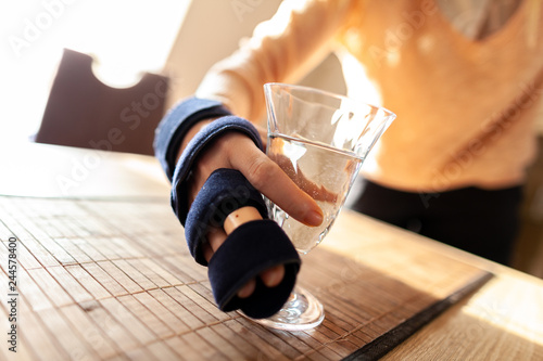 Hand holds a glass of water with a medical hand sling