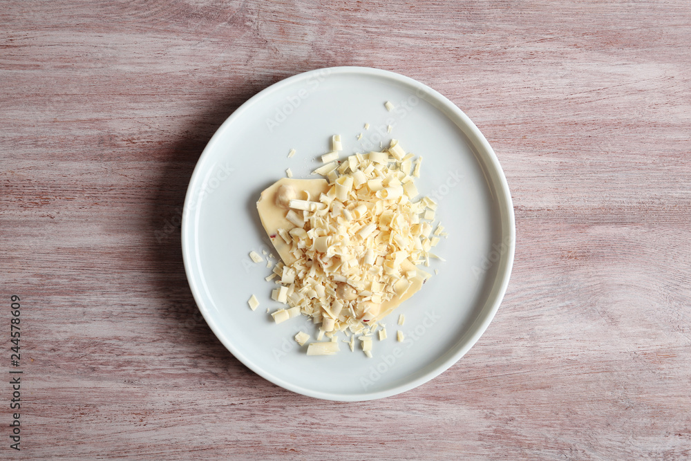 Plate with white chocolate curls on wooden background, top view Plate with white chocolate curls on wooden background, top view