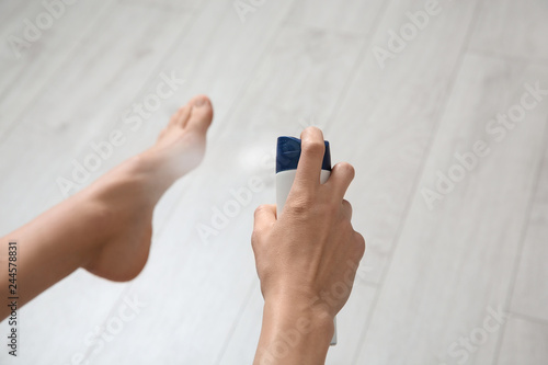 Young woman using deodorant for feet at home, closeup
