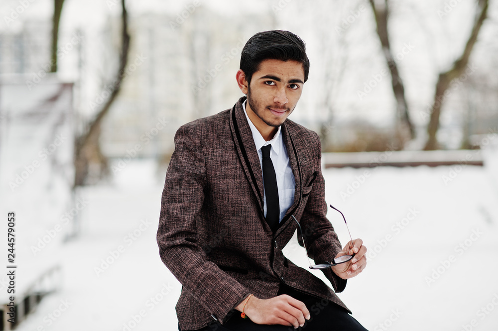 Stylish indian student man in suit and glasses posed at winter day outdoor. Stylish indian student man in suit and glasses posed at winter day outdoor.
