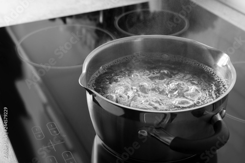 Pot with boiling water on electric stove, space for text photo