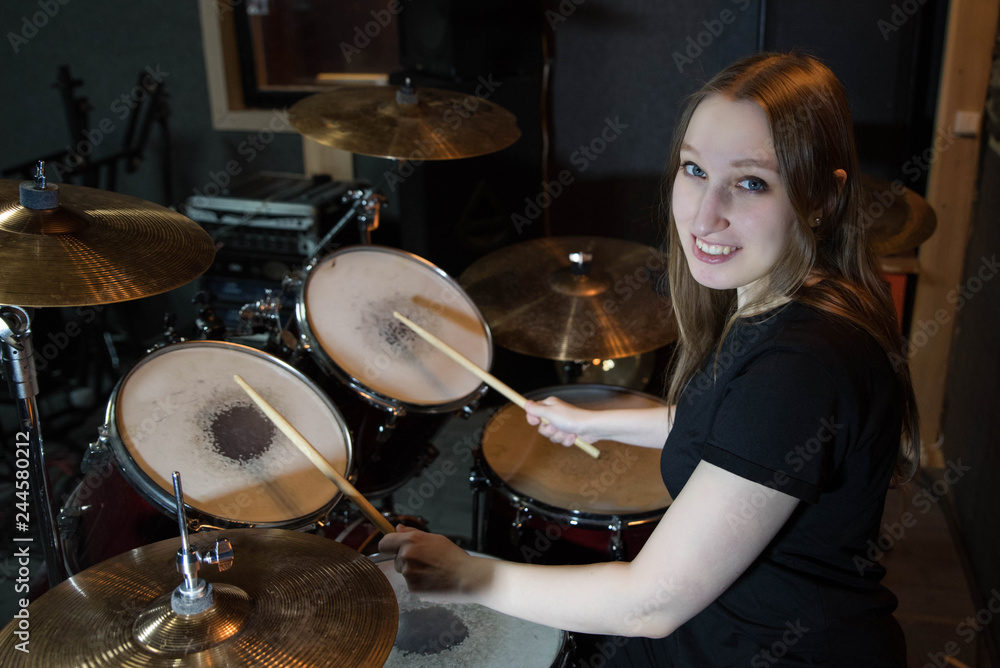 Obraz premium Professional drum set closeup. Beautiful young girl drummer with drumsticks playing drums and cymbals, on the live music rock concert or in recording studio 
