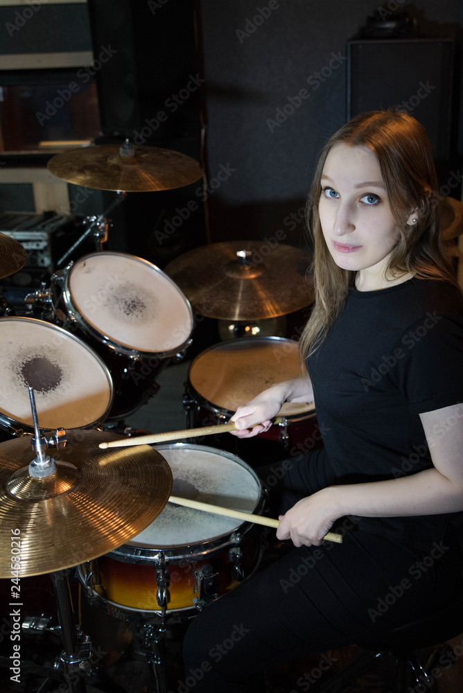 Professional drum set closeup. Beautiful young girl drummer with drumsticks playing drums and cymbals, on the live music rock concert or in recording studio Professional drum set closeup. Beautiful young girl drummer with drumsticks playing drums and cymbals, on the live music rock concert or in recording studio