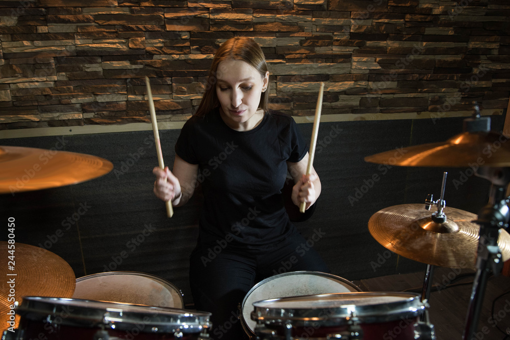 Fototapeta premium Professional drum set closeup. Beautiful young girl drummer with drumsticks playing drums and cymbals, on the live music rock concert or in recording studio
