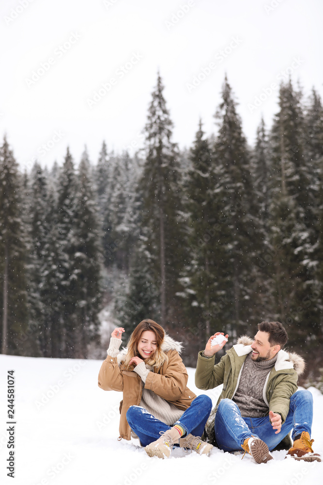 Fototapeta premium Couple spending time outdoors on snowy day, space for text. Winter vacation