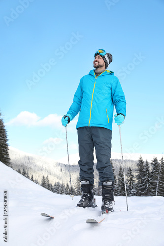 Man with ski equipment spending winter vacation in mountains