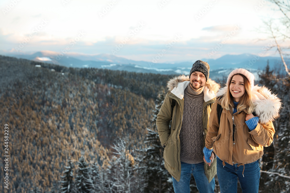Happy couple spending winter vacation together in mountains. Space for text