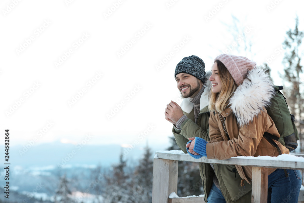 Fototapeta premium Couple with backpacks enjoying mountain view during winter vacation. Space for text