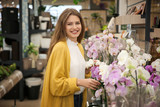 Beautiful young woman with orchids in flower shop