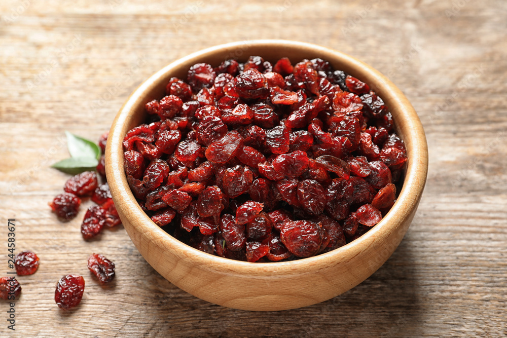 Bowl with cranberries on wooden table. Dried fruit as healthy snack Bowl with cranberries on wooden table. Dried fruit as healthy snack