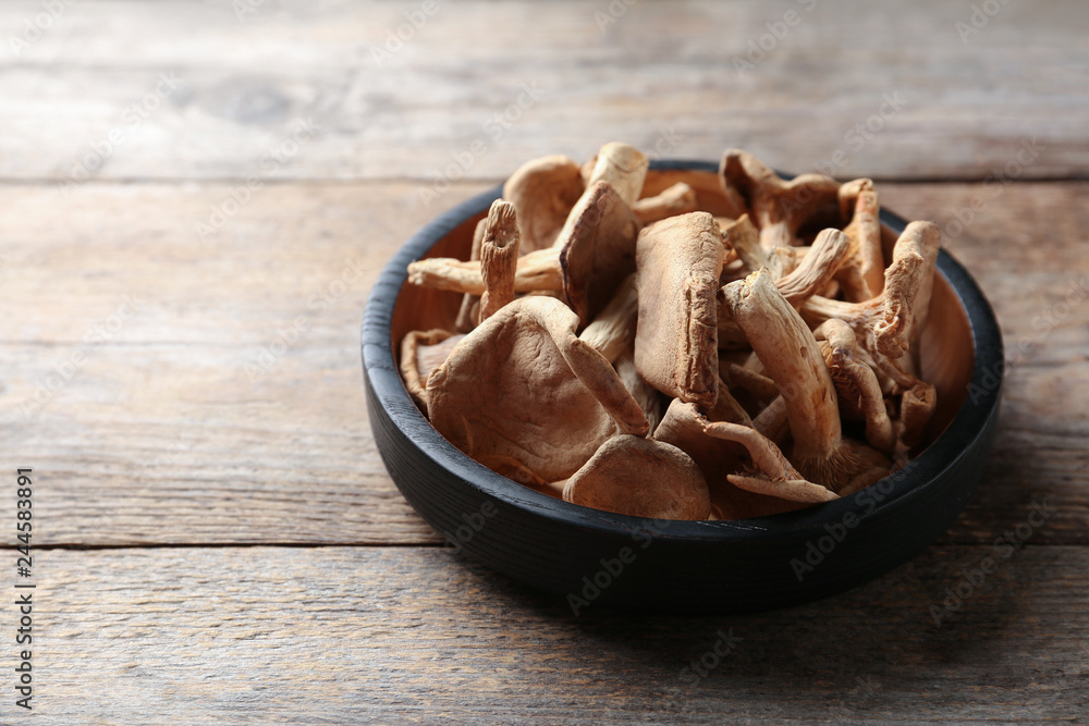 Plate of dried mushrooms on wooden background. Space for text Plate of dried mushrooms on wooden background. Space for text