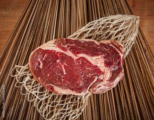 Raw Ribeye Steak on a wood backdrop 