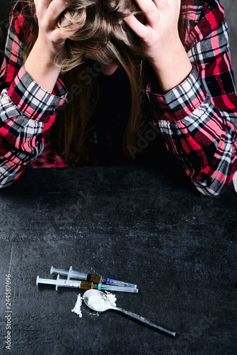 Foto Young woman and syringe with heroin or cocaine on table