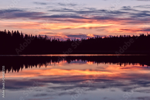 sunset clouds are reflected in the calm mirror water of the lake