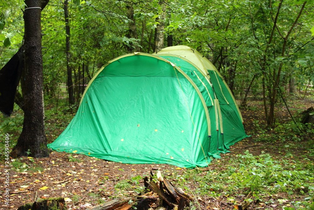 Large green camping tent in the forest on a summer day - sports tourism, camping, scouting