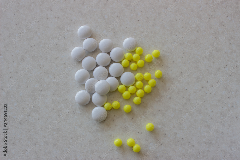 Yellow and white tablets on white surface Yellow and white tablets on white surface