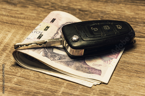 Car keys and banknotes as the concept of buying or renting a car. Loan for buying a car. Czech money at the table. Financial concept with money.