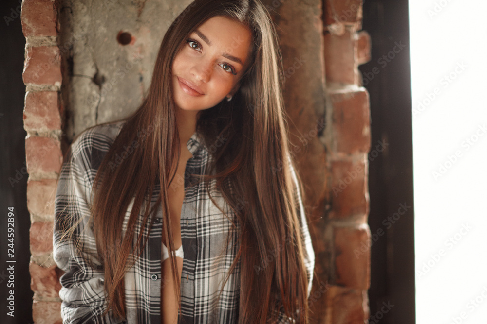 Fototapeta premium Young woman posing indoor with christmas tree in winter decor studio. 