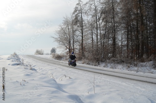 road in winter forest and a scooter