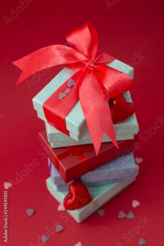 Many colorful gift boxes on red background. Valentine's day, mother's Day, birthday or party concept. Hearts decorations. Copy space. photo