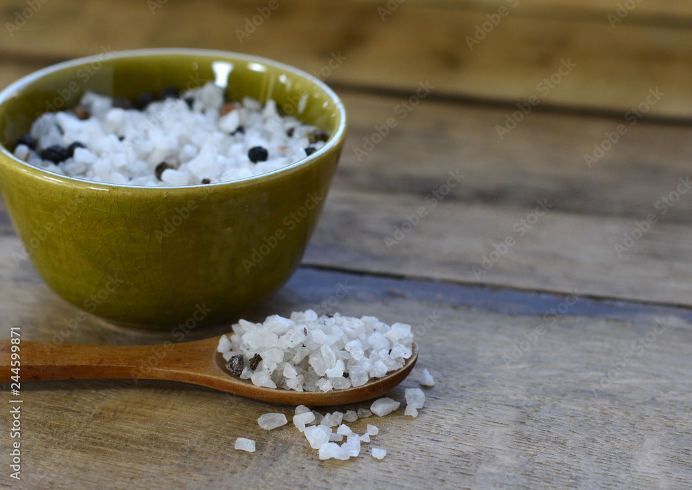sea salt with pepper and spices . sea salt in bowl with wooden spoon on wooden background. sea salt with pepper and spices . sea salt in bowl with wooden spoon on wooden background.