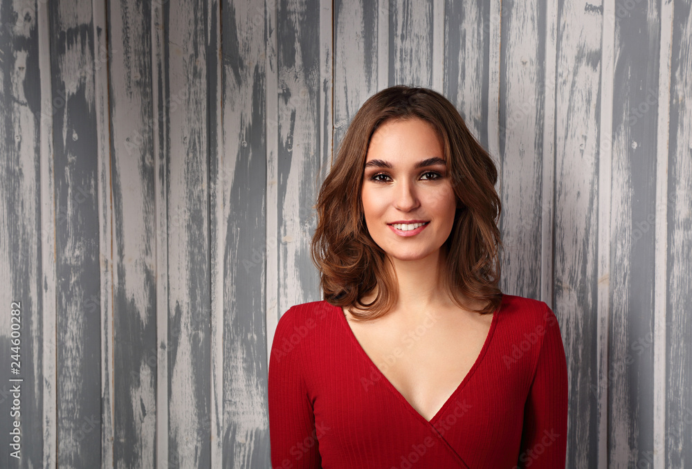Fototapeta premium Beautiful positive toothy smiling woman and looking happy in casual red shirt and short curly hair