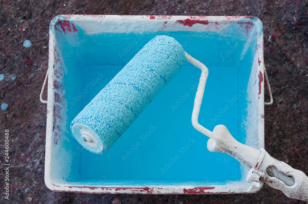 Obraz premium paint roller in a bucket with blue paint