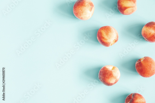 Peaches on pastel blue background. Frame made of fresh peashes. Flat lay, top view, copy space