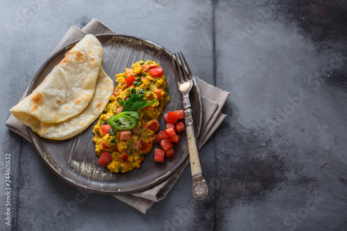 Scrambled eggs with tomatoes and chives on a plate, copy space