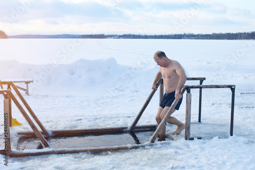 Ice hole on the lake. A man bathes in ice water.