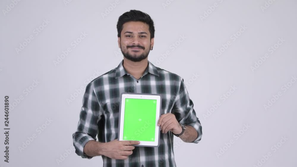 Portrait of young happy bearded Indian man showing digital tablet Portrait of young happy bearded Indian man showing digital tablet