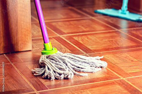 Rope mop for cleaning the floor is on the floor of the tile.