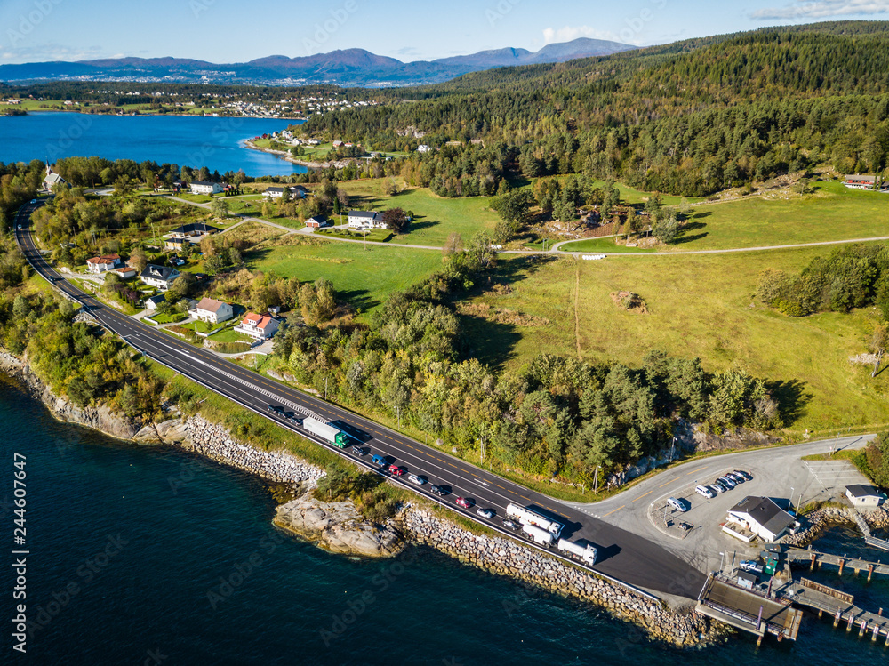 Obraz premium Drone Photo of the Cars Waiting in Line on Ferry Port in Langfjorden in Norway on a Sunny Summer Day with Mountains and Blue Skies in the Background