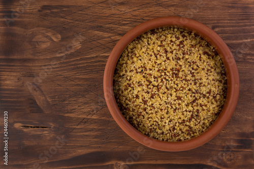 bowl of raw bulgur and quinoa on wooden table background
