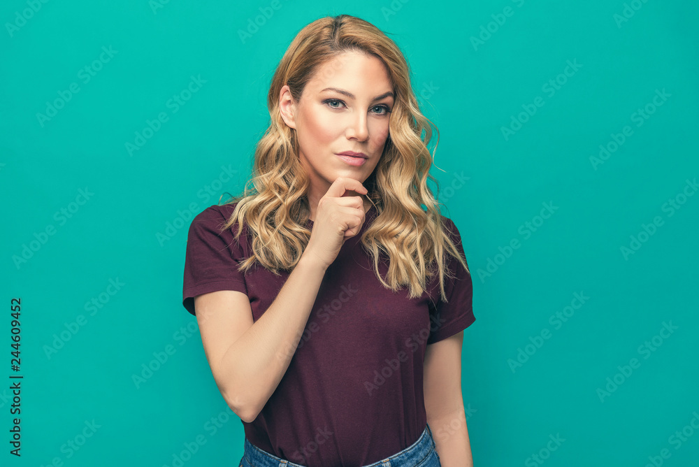 Young attractive blonde on a blue background. Beautiful woman posing on trendy background dressed in fashionable youth clothes. Young attractive blonde on a blue background. Beautiful woman posing on trendy background dressed in fashionable youth clothes.