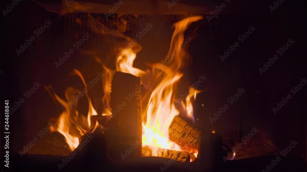 Close-up of glowing burning in fireplace log covered by flame fire Close-up of glowing burning in fireplace log covered by flame fire