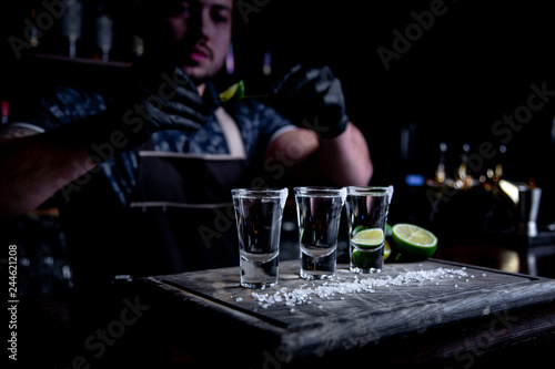 aperitif with friends in the bar, three glasses of alcohol with lime and salt for decoration. Tequila shots, selective focus photo