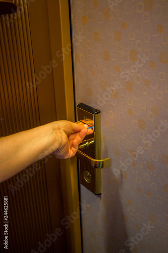 hand inserting a key card into a hotel room electronic door security lock to unlock the door
