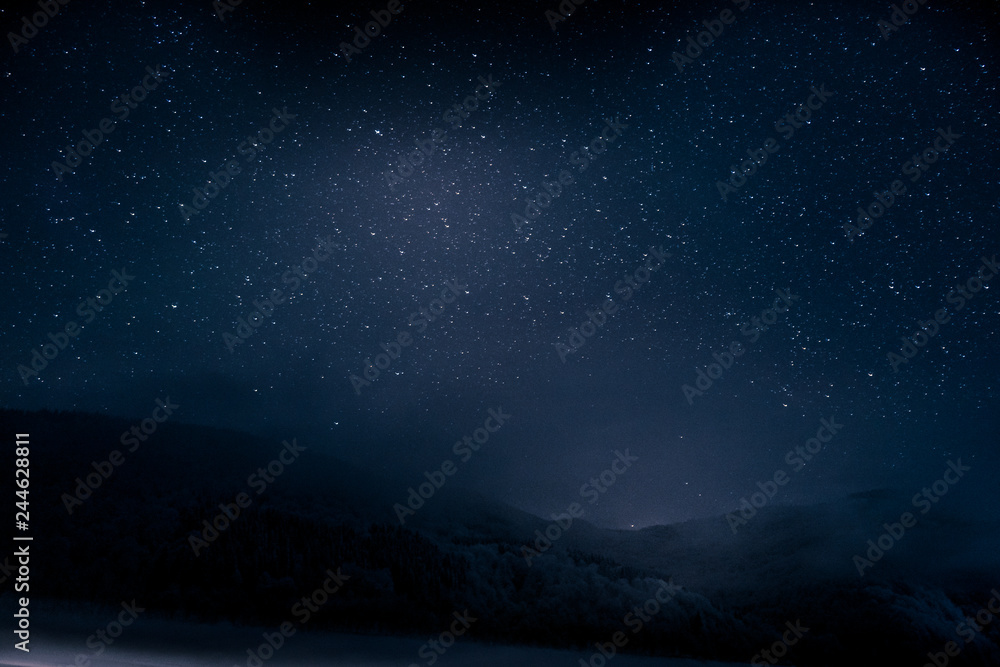 Beautiful blue dark night sky with many stars above snowy mountains