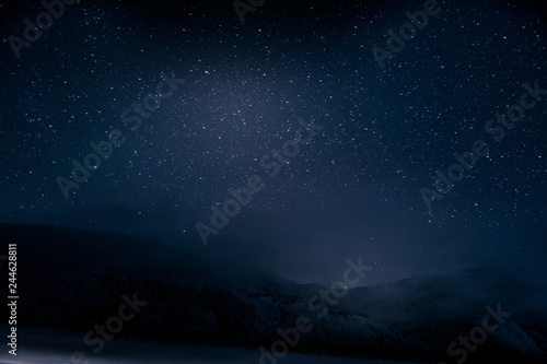 Beautiful blue dark night sky with many stars above snowy mountains