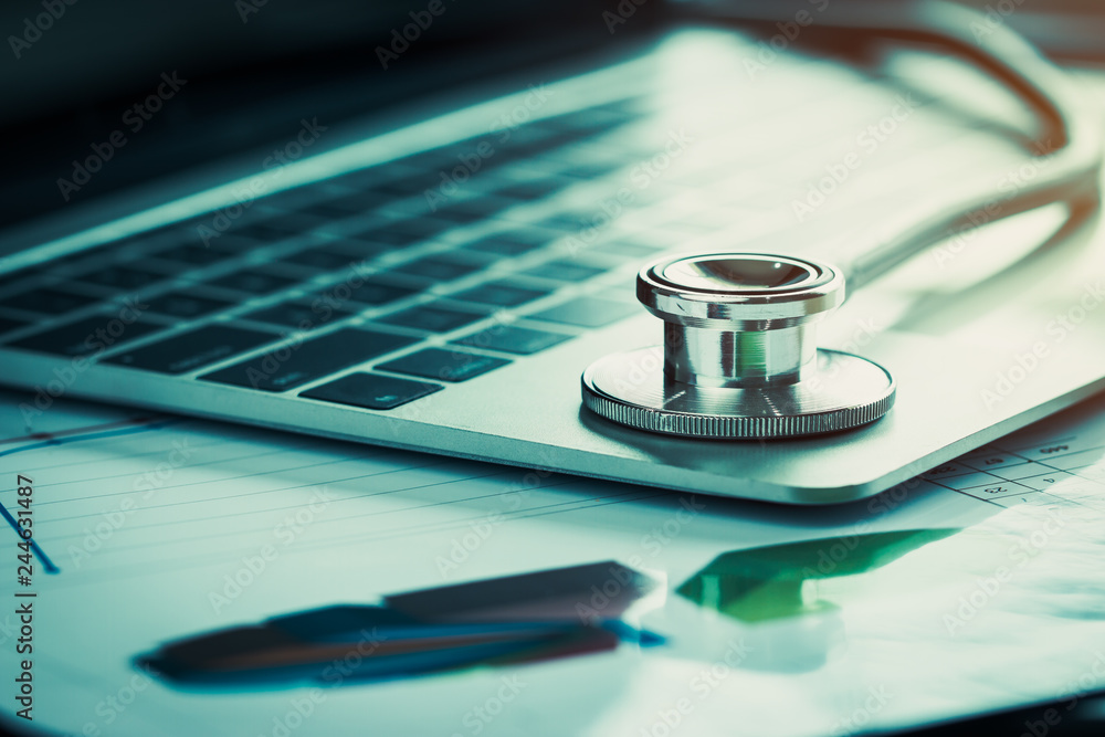 Stethoscope on computer with test results in Doctor consulting room background and report chart for medical costs in modern hospital on Laptop desk. Healthcare costs business, fees concept. Gray tone Stethoscope on computer with test results in Doctor consulting room background and report chart for medical costs in modern hospital on Laptop desk. Healthcare costs business, fees concept. Gray tone