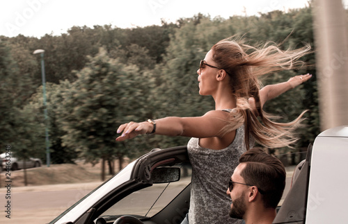happy young woman standing in convertible car