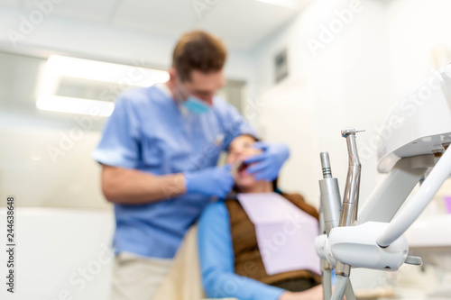 Dentist performing teeth treatment with female patient blurred  focus on tools
