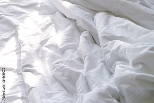 Top view of white unmade bedsheet on a bed in bedroom with beautiful sunlight