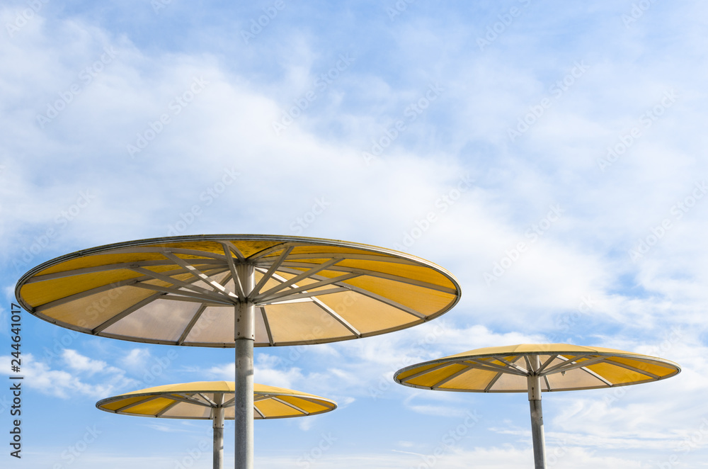 Three yellow parasols against blue sky